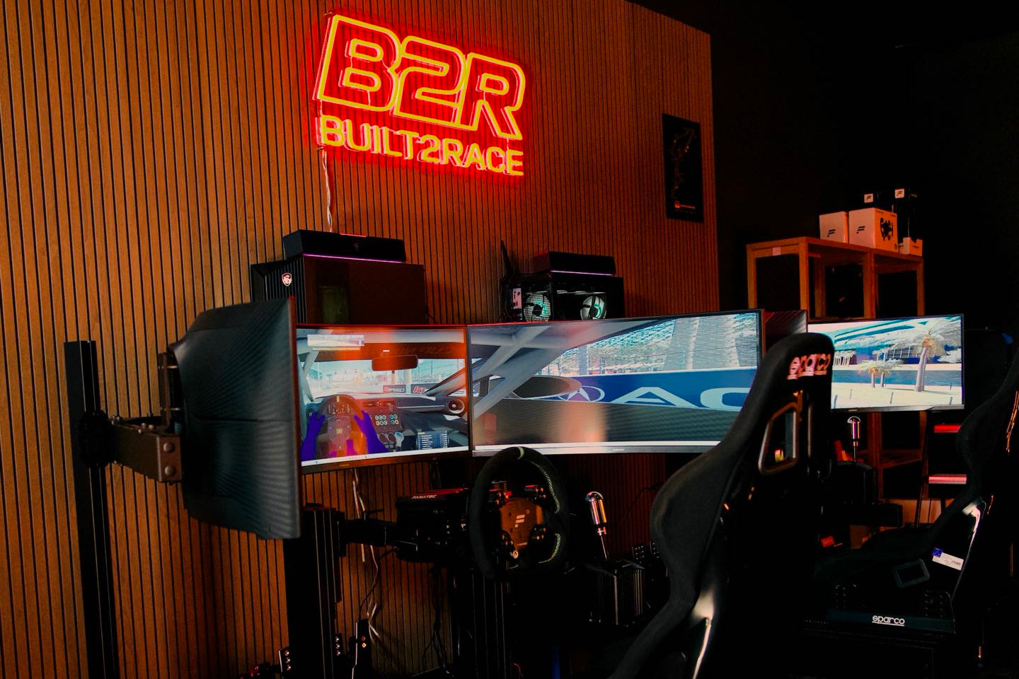 Simulator setup with multiple screens and a neon sign on the wall.